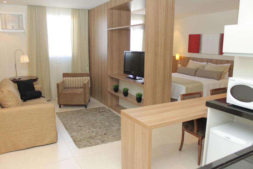 a hotel room with a bed and a living room at Faria Lima Flat Service in Sao Jose do Rio Preto