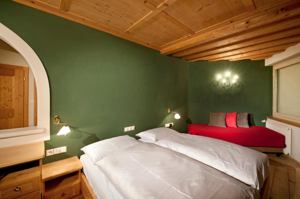 1 dormitorio con cama blanca y pared verde en Residence Adler en Villabassa