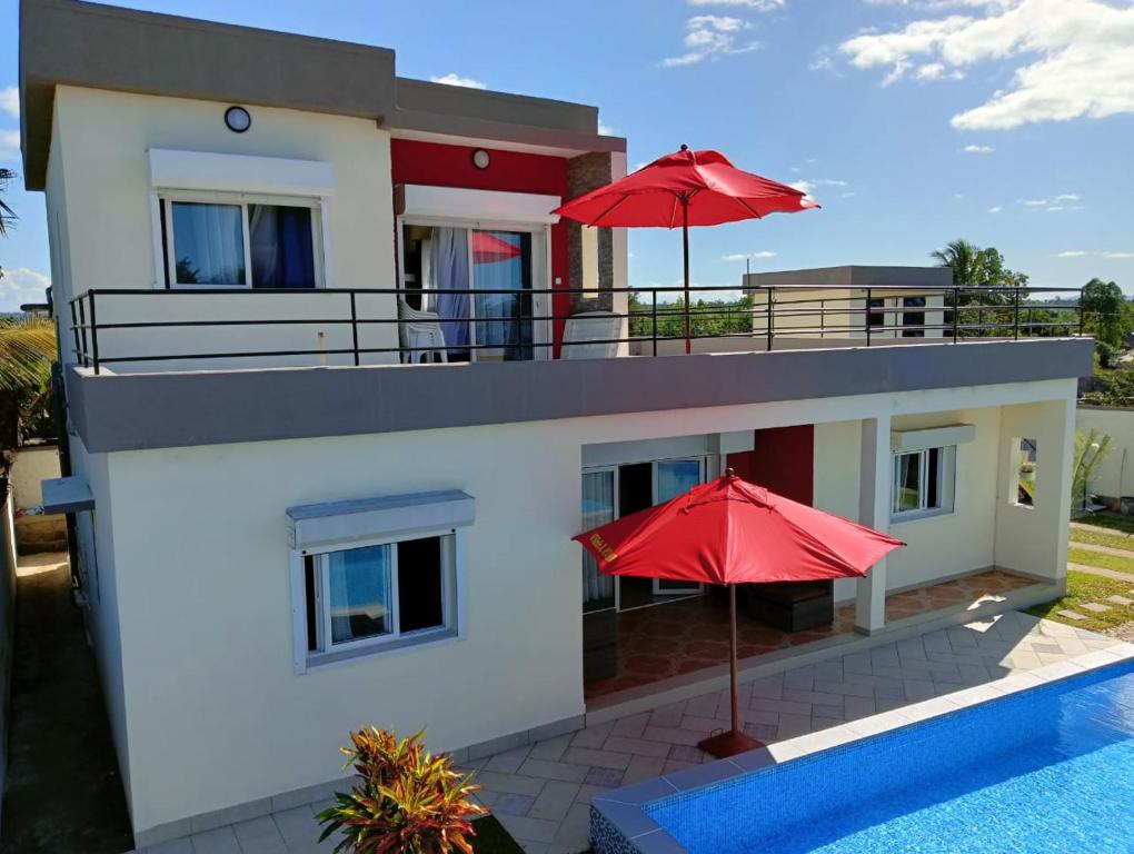 a house with two red umbrellas next to a swimming pool at Villa de vacances privative in Toamasina