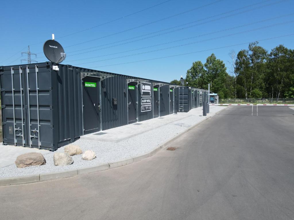 un parking avec une rangée de conteneurs noirs dans l'établissement Roatel Schipkau (A13) my-roatel-com, à Schipkau