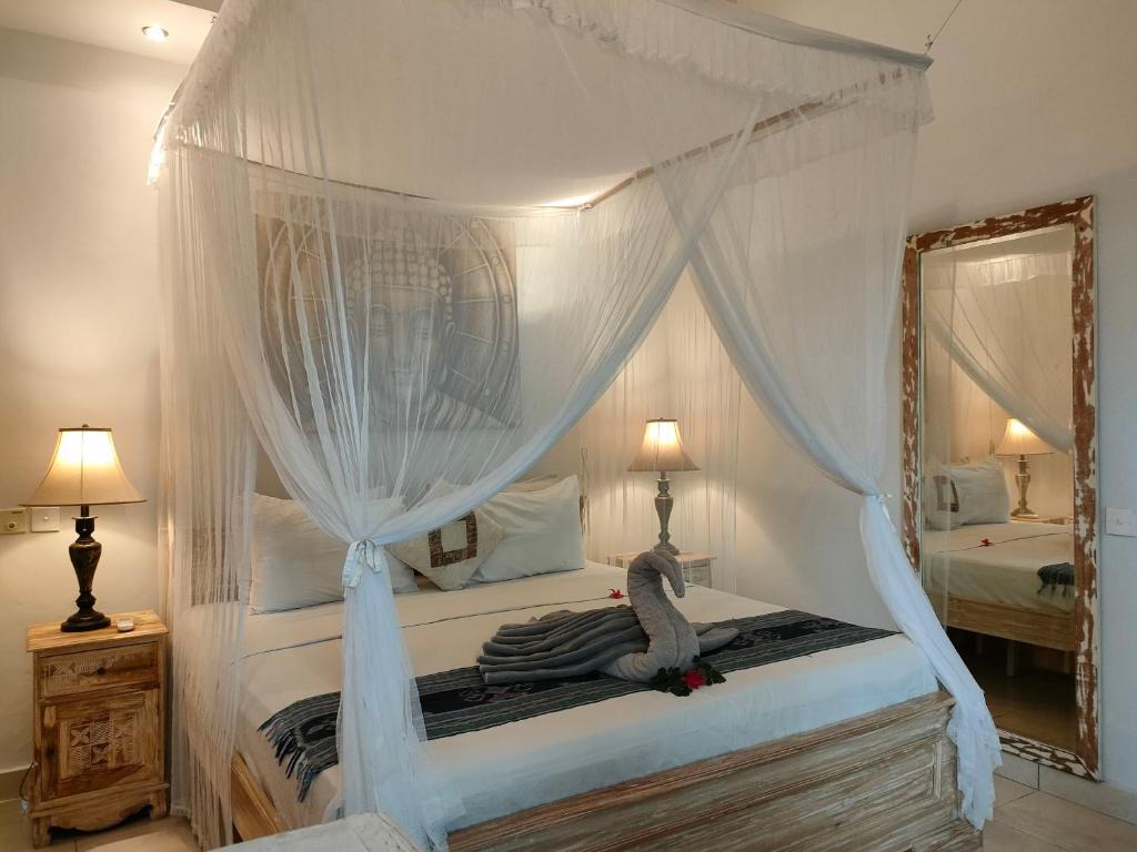 - une chambre dotée d'un lit à baldaquin avec un animal farci dans l'établissement Candra Surf Homestay, à Canggu