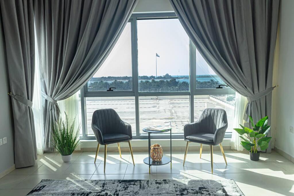 アブダビにあるSuper 2 Bedroom Sea Viewの大きな窓の前に椅子2脚とテーブル