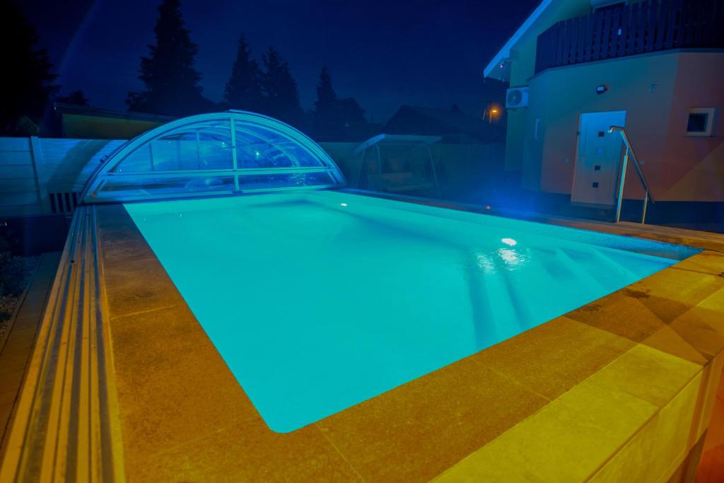 a swimming pool at night with blue lighting at LuxVil Apartman in Balatonkeresztúr