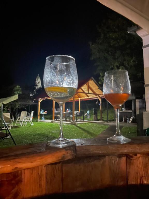 dos copas de vino sentadas sobre una barandilla de madera en Casa De Sub Deal en Densuş