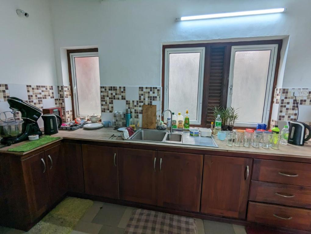 a kitchen counter with a sink and two windows at Shiranthi Guest House in Rajagiriya