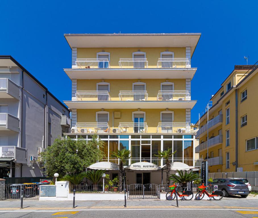 um edifício amarelo com bicicletas estacionadas em frente em Hotel Austria em Rimini