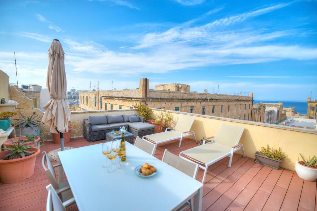 eine Terrasse mit einem Sofa und Stühlen auf dem Dach in der Unterkunft Comfy 1 bedroom - Sun terrace & sea views GBUH1-1 in Valletta