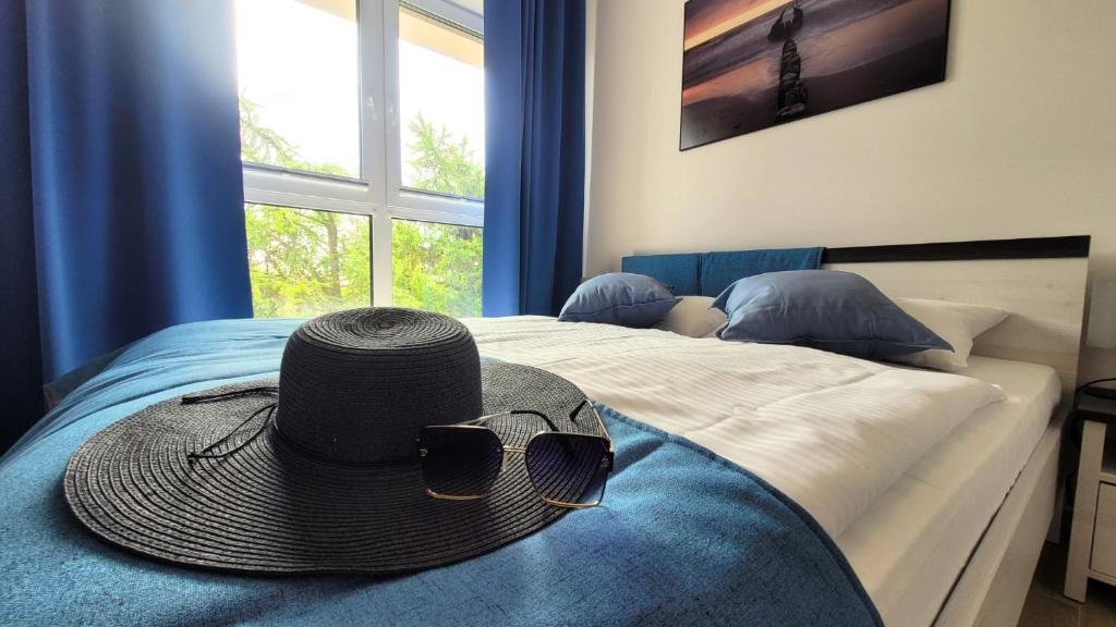un cappello e occhiali da sole seduti sopra un letto di Apartamenty Lambert Ustronie Morskie a Ustronie Morskie