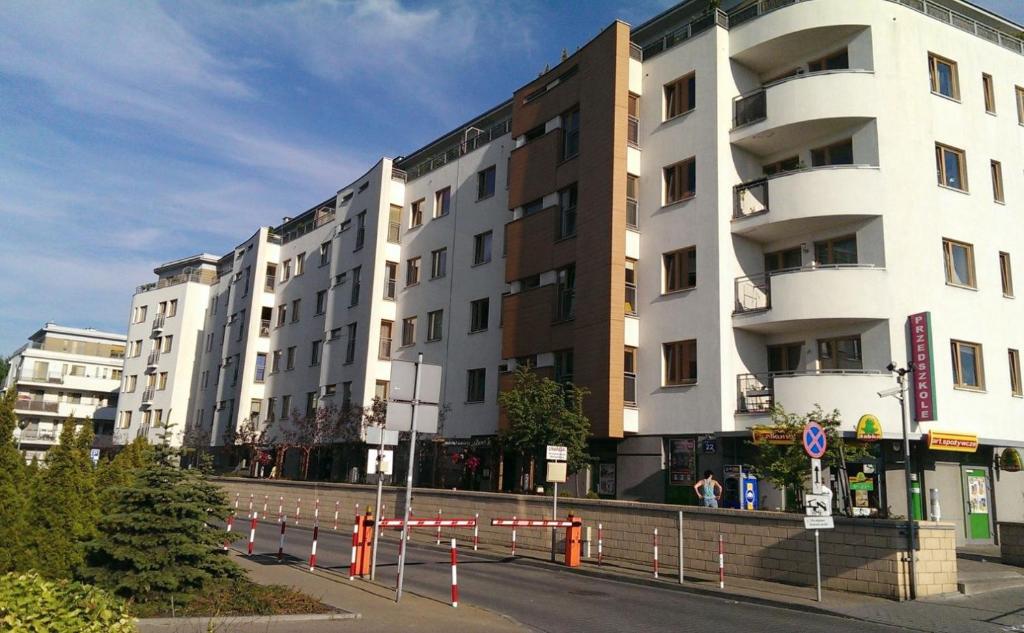 un bâtiment situé dans une rue avec des barrières orange devant elle dans l'établissement Warszawa Bemowo Pokoje, à Varsovie