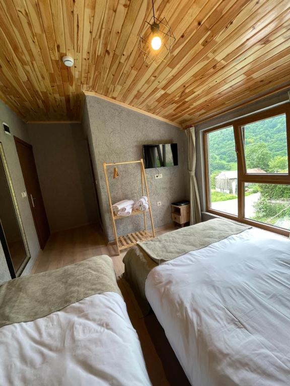 een slaapkamer met 2 bedden en een groot raam bij Bizim O'ra Küme Evleri & Bungalov in Trabzon