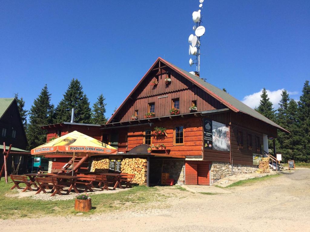 a large wooden building with tables and an umbrella at Kiosek U Staré Lanovky in Janske Lazne