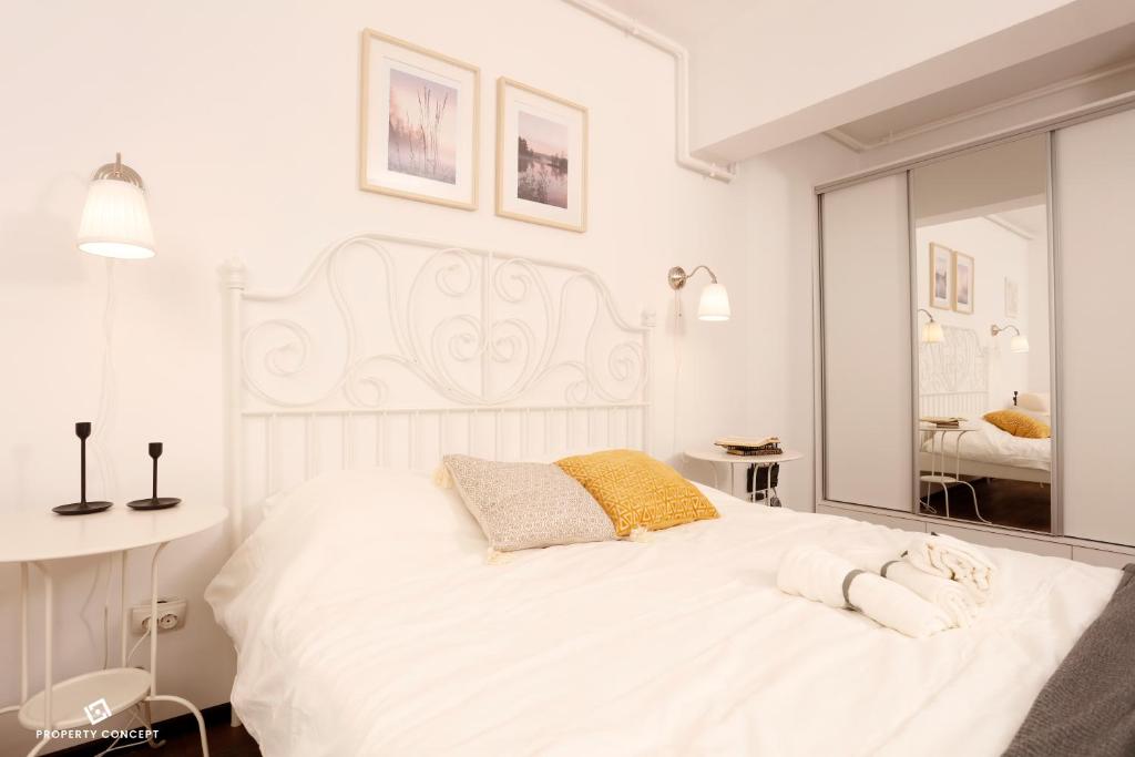a white bedroom with a large white bed and a mirror at Elegant Concept Studio in Bucharest