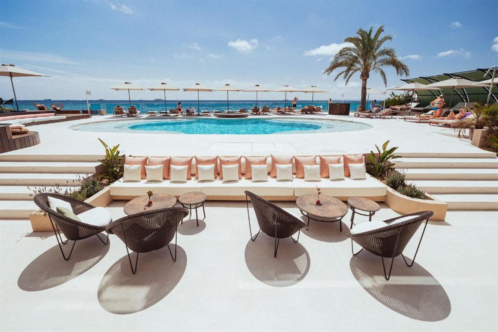 a resort with a pool and tables and chairs at AMA Ibiza in Playa d'en Bossa
