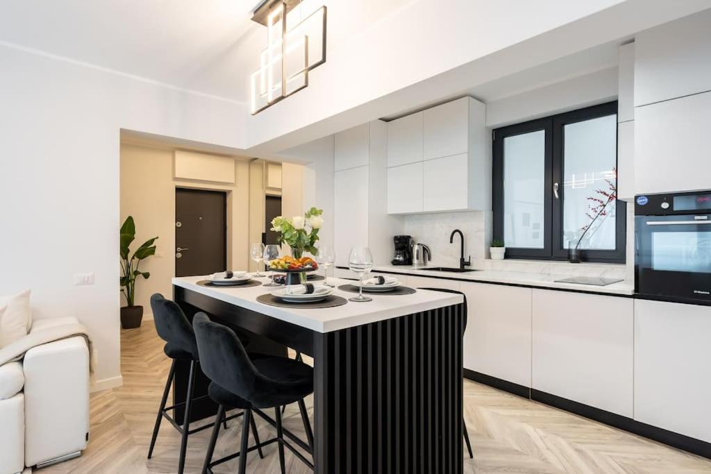 a kitchen with a black and white kitchen island with chairs at Mellow - Calea Victoriei - 2BR Luxury Apartment in Bucharest