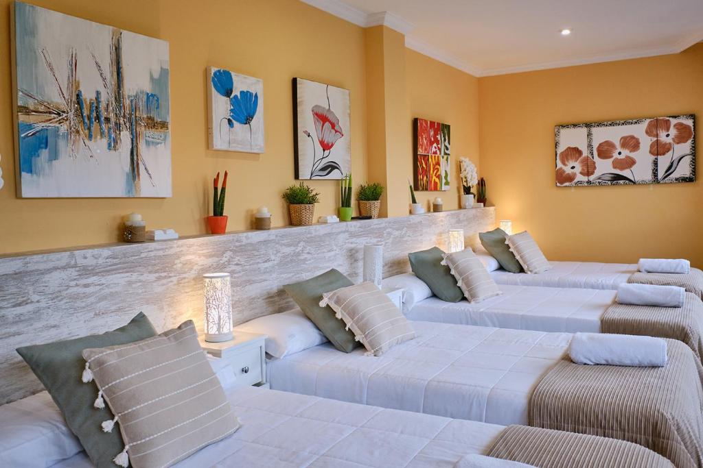 Una sala de estar con tres camas con almohadas. en Peregrina Pensión 1, en O Pedrouzo