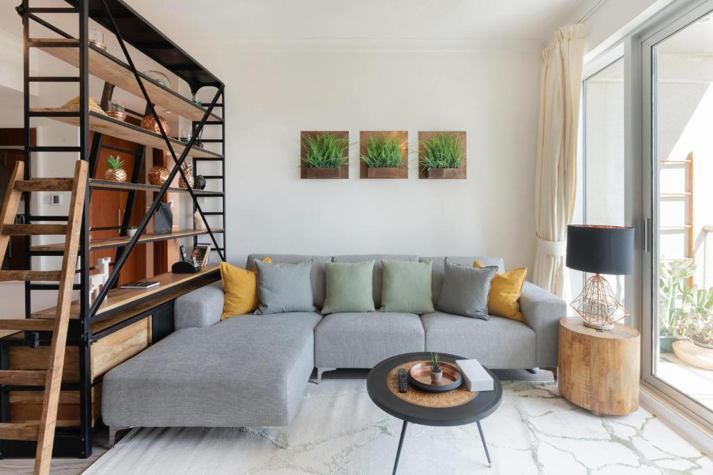 uma sala de estar com um sofá e uma escada em espiral em Fairways West Tower - 1BR Apartment - Allsopp&Allsopp em Dubai