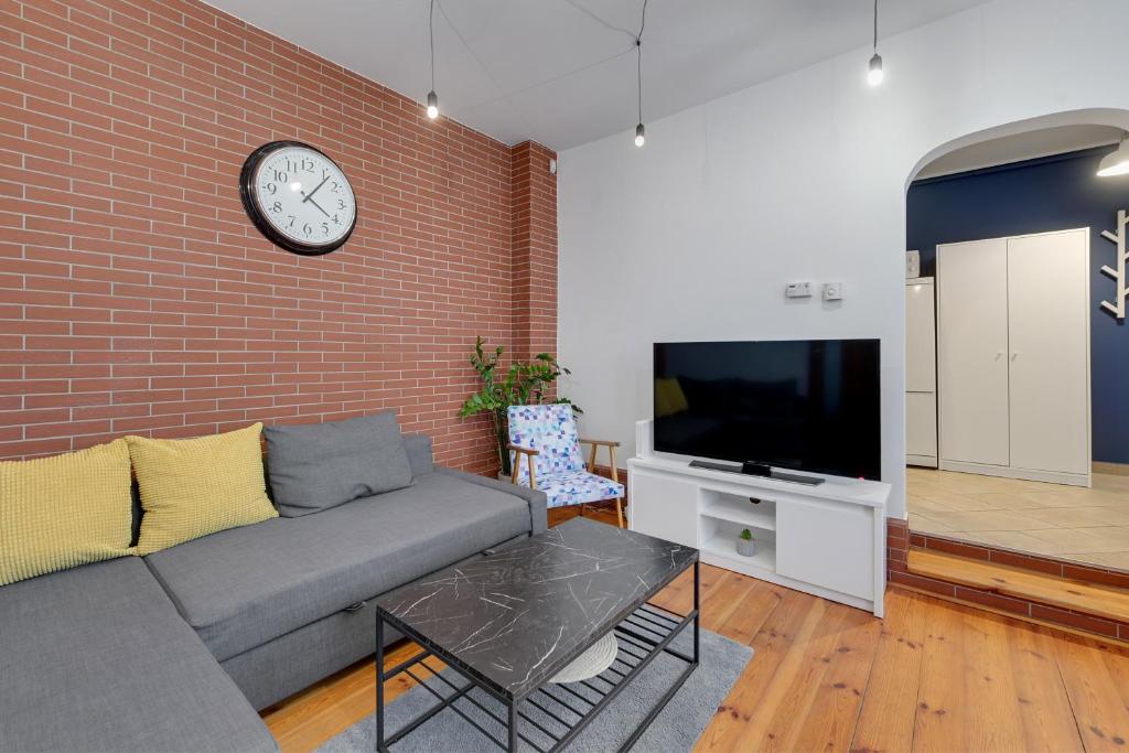 a living room with a couch and a clock on a brick wall at Grand Apartments - Balticana Apartment in Sopot