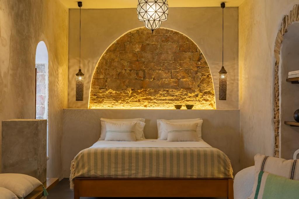 um quarto com uma cama com uma parede de pedra em The Riad - Adults Only em Tarifa