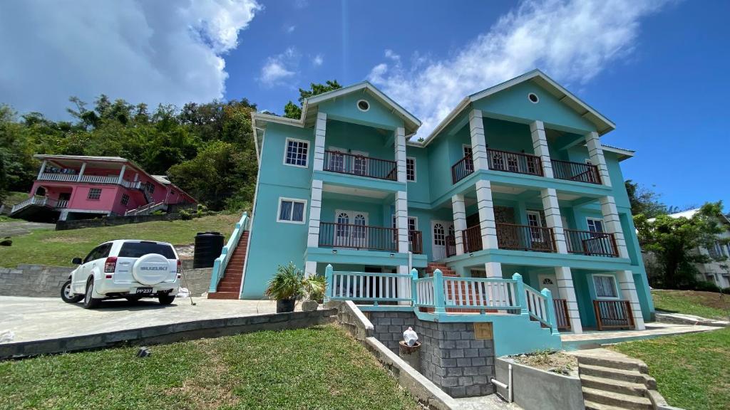 a blue house with a car parked in front of it at Golden Palms Apartment in Kingstown