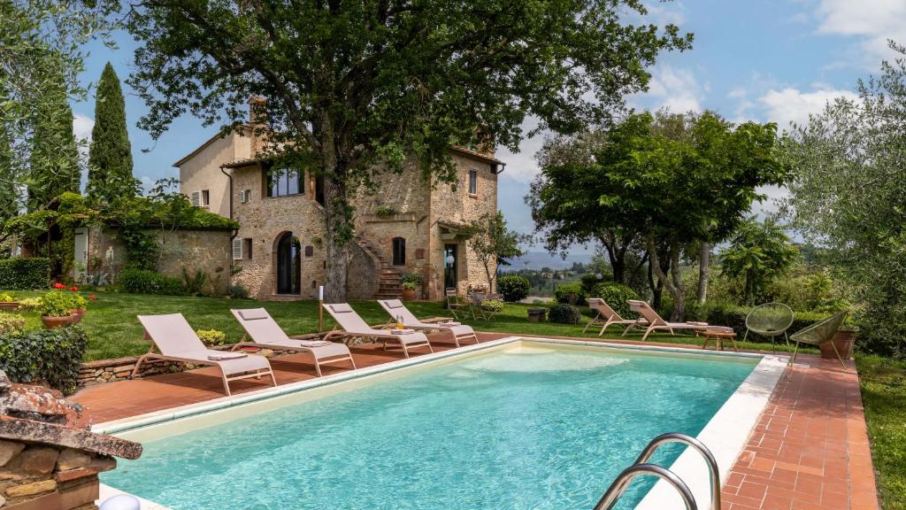 a swimming pool with lounge chairs and a house at Villa Caterina 8, Emma Villas in San Gimignano