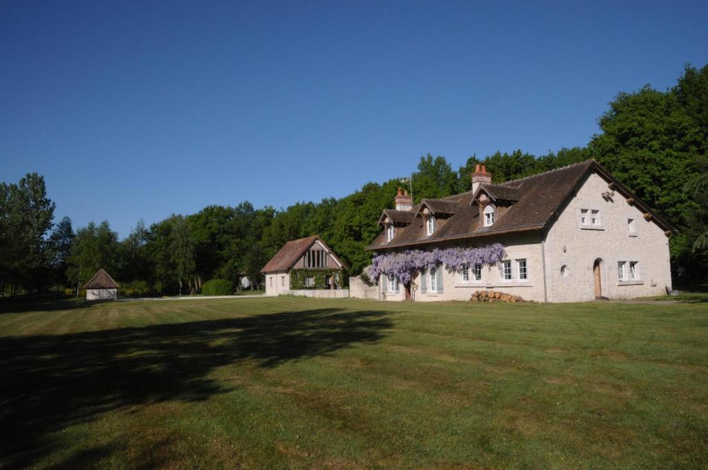 a large white house with purple flowers on a field at Chambre d'hôtes Domaine de la Pépinière in Chouzy-sur-Cisse