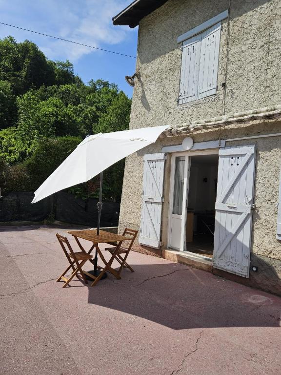 un tavolo da picnic con un ombrello bianco di fronte a un edificio di Gîte de l'Eau Vive a Saint-Martin-dʼUriage