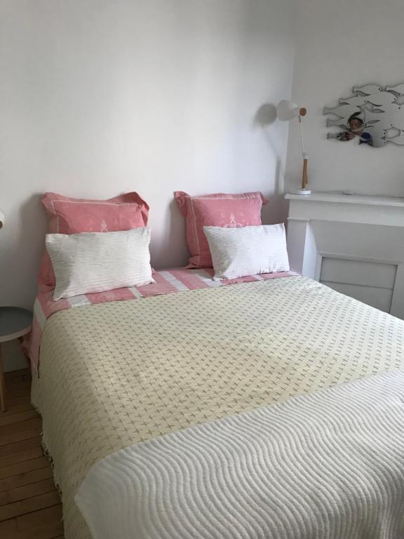 een bed met roze en witte lakens en roze kussens bij Sweet Room 15 in Parijs