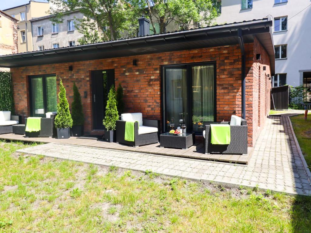 a brick building with green and white chairs on a patio at Sander Apartments in Kraków