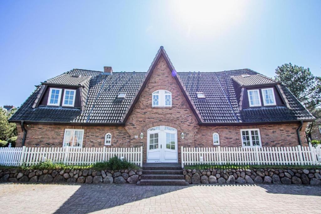 a large brick house with a white fence at Appartement-Mecking in Munkmarsch