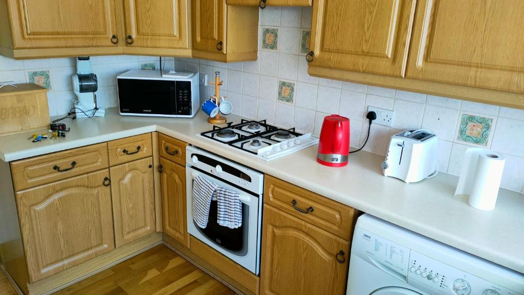 a kitchen with wooden cabinets and a stove top oven at Linksway House in Birkenhead