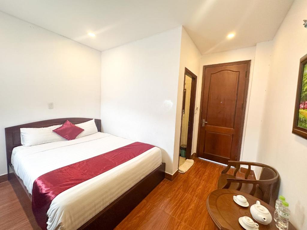 ダラットにあるWhite Horse Dalat Hotelのベッドと木製のテーブルのある寝室