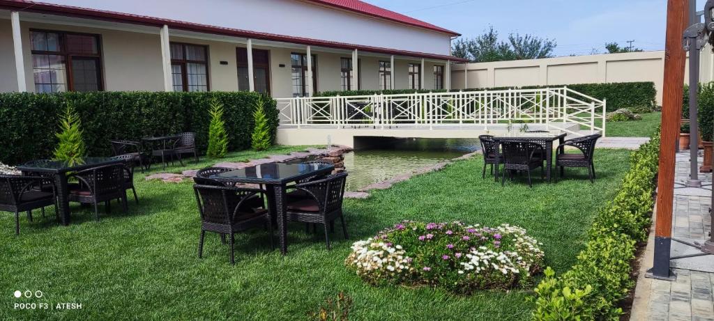 Very Well Guest House في باكو: فناء به طاولات وكراسي على العشب