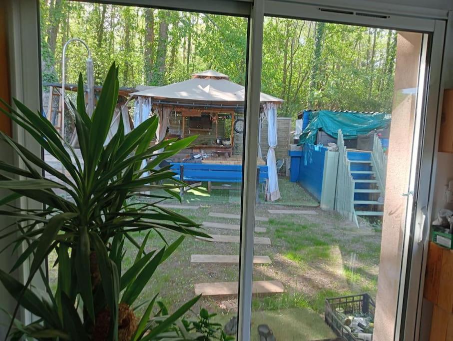 una ventana con vistas a un patio trasero con cenador en maison 70m2 calme vue sur forêt, en Salles