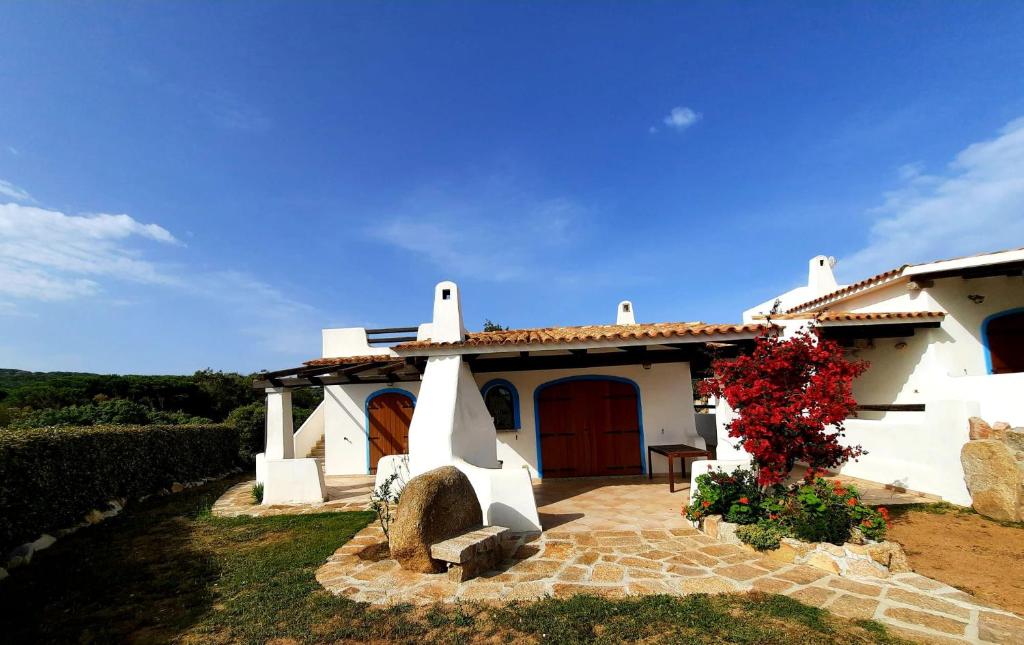 ein kleines weißes Haus mit einer roten Tür in der Unterkunft Villa Cala d'Oro santa teresa di gallura in Santa Teresa Gallura
