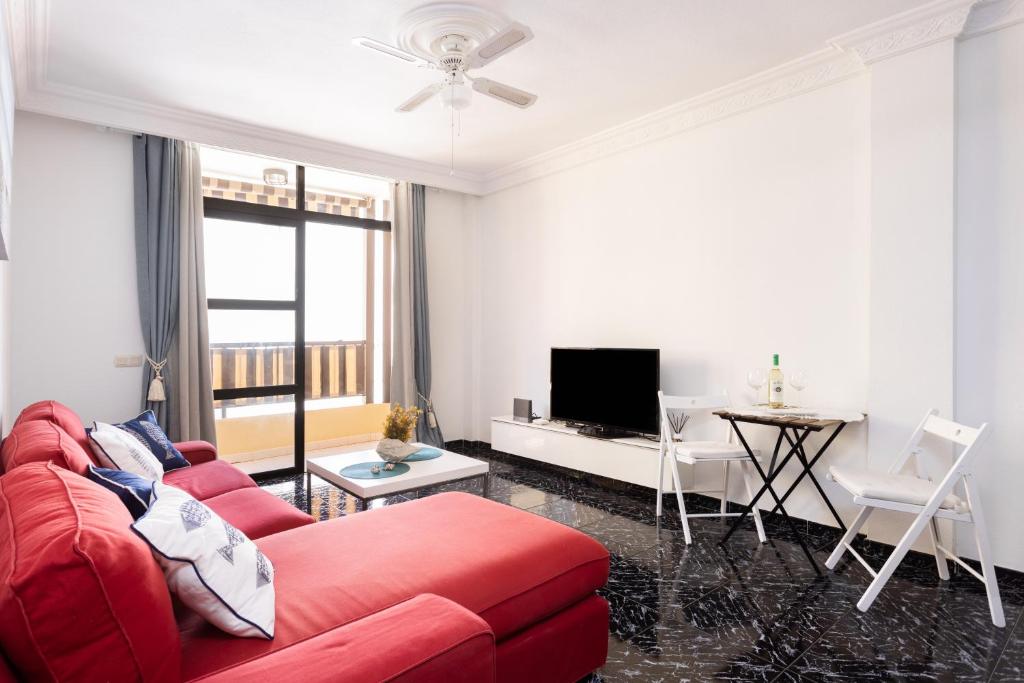 a living room with a red couch and a table at Home2Book Percy Apartment El Médano Beach in El Médano