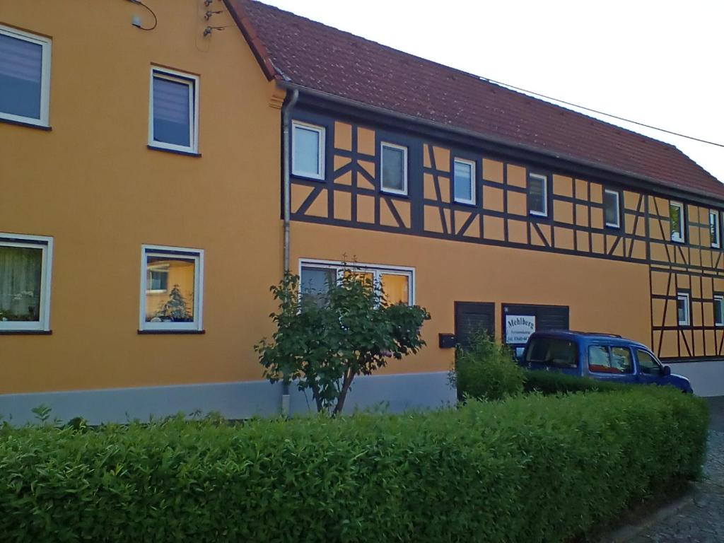 a yellow house with a black roof at Ferienwohnung Mehlberg in Großlöbichau