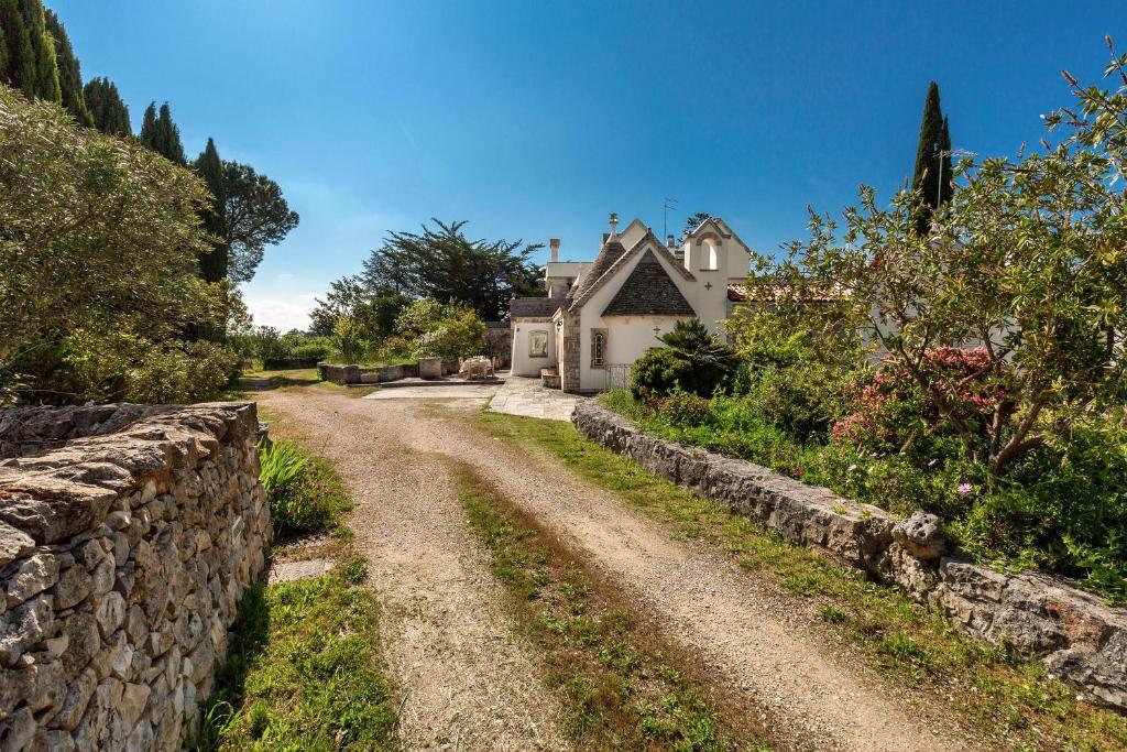 een onverharde weg die leidt naar een huis met een stenen muur bij Villa Poggio dei Loti by BarbarHouse in Cisternino