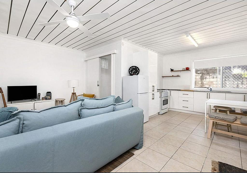 a living room with a blue couch and a kitchen at Cooly Coastal Escape walk to beach & shops in Gold Coast