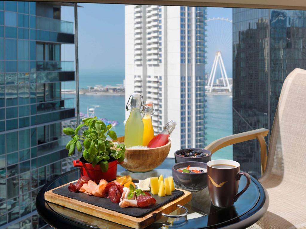 a tray of food on a table with a view of a city at Mövenpick Hotel Jumeirah Beach in Dubai