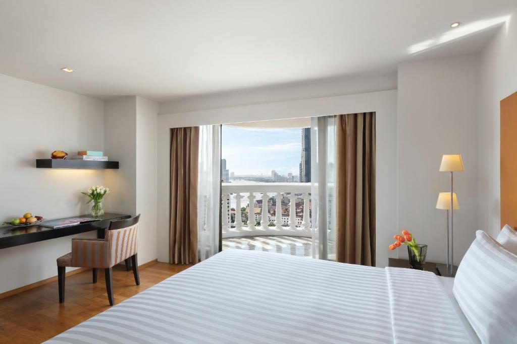 a hotel room with a bed and a desk and a window at lebua at State Tower in Bangkok
