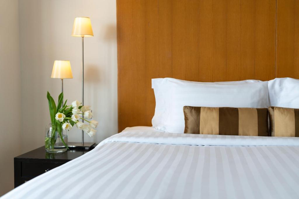 a bedroom with a large white bed with a wooden headboard at lebua at State Tower in Bangkok