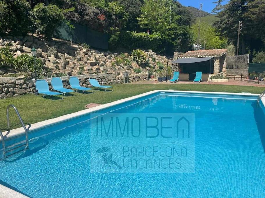 - une grande piscine avec des chaises bleues dans la cour dans l'établissement Bv-am 001-can Palome., à Arenys de Munt