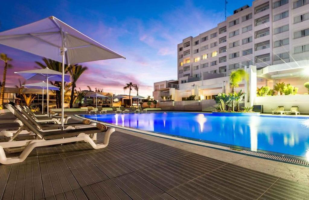 a pool at a hotel with chairs and an umbrella at Sahara Hotel Agadir - Adults Only in Agadir