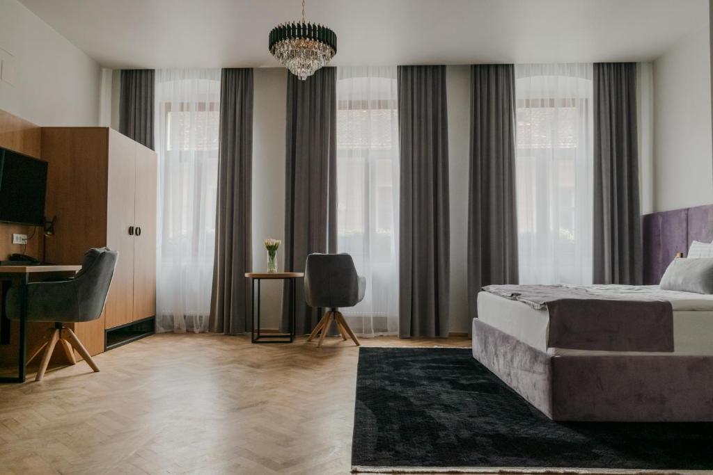 a bedroom with a bed and a desk and windows at Prinz Gregor in Braşov
