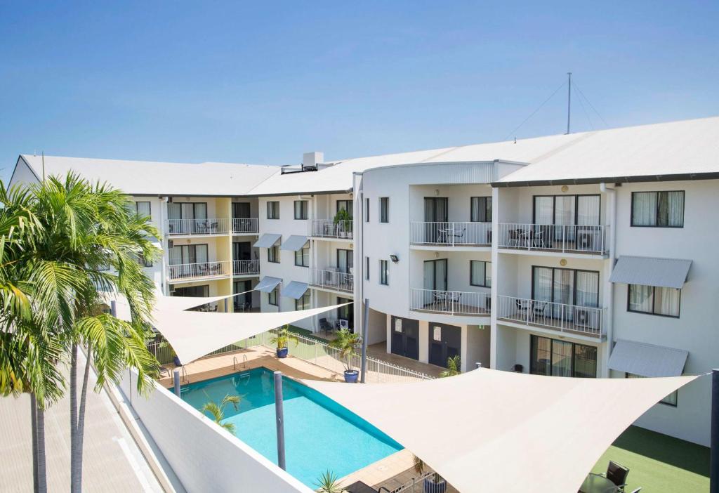 an apartment building with a swimming pool and palm trees at Metro Advance Apartments & Hotel in Darwin