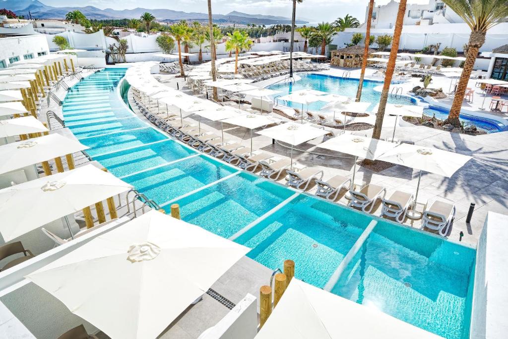 ein Bild eines Pools in einem Resort mit weißen Sonnenschirmen in der Unterkunft Labranda Golden Beach Only Adults in Costa Calma