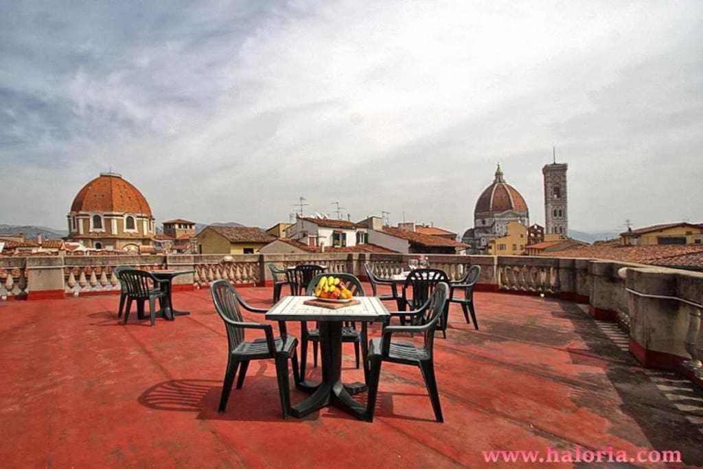 eine Terrasse mit Tischen und Stühlen auf dem Dach in der Unterkunft Spettacolare Vista Duomo Con Terrazza in Florenz