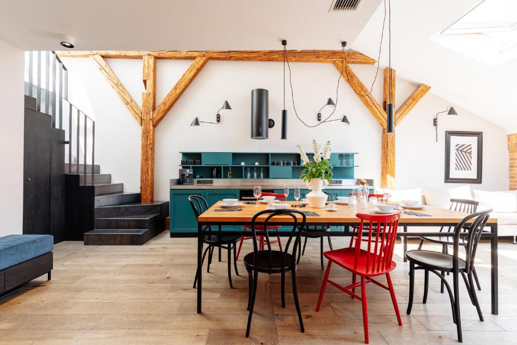 een keuken en eetkamer met een houten tafel en rode stoelen bij Penthouse Stradom by LoftAffair in Krakau