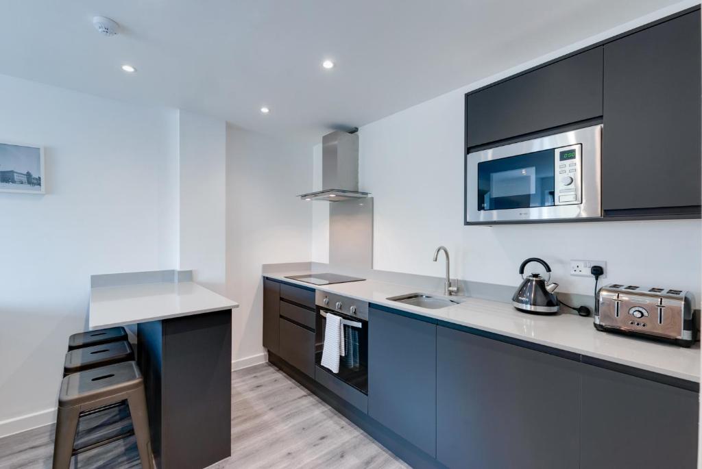 a kitchen with black and white counters and a microwave at Liverpool Short Stay Apartments in Liverpool