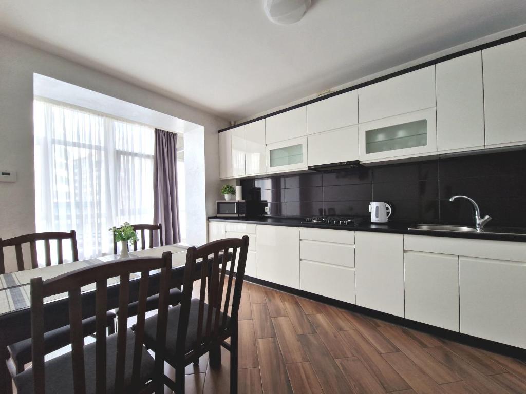 a kitchen with white cabinets and a table with chairs at Apartment on Belvedere in Ivano-Frankivsk